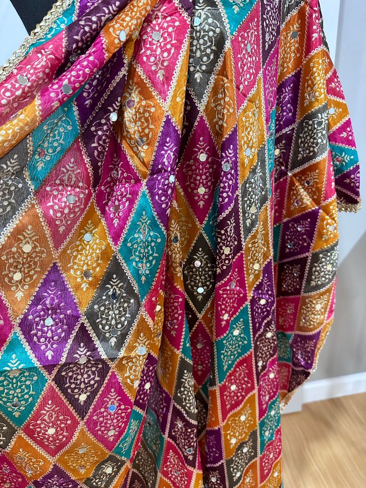 Experience the beauty of traditional Phulkari style with our Multicolor Dupatta. Made with a soft and luxurious silk finish, this dupatta features real mirror accents and stunning designs. Its heavy-weight construction makes it perfect for special occasions like Navaratri. Elevate your wardrobe with this must-have accessory. Approx 2.5 meters length Festivals Semi-stitched Sharara With Motifs, Multicolor Semi-stitched Jamawar Dupatta, Bollywood Style Dola Silk Saree With Multicolor Embroidery, Festive Embroidered Dupatta For Celebration, Festive Embroidered Celebration Dupatta, Unstitched Katan Silk Traditional Wear With Gota Work, Silk Sharara With Multicolor Embroidery For Navratri, Bollywood Style Chanderi Saree With Multicolor Embroidery, Festive Jamawar Sharara With Dupatta