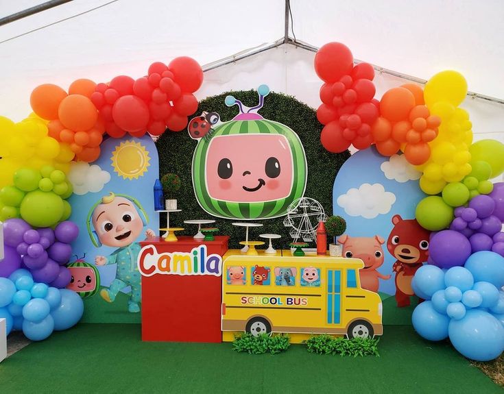 an outdoor area with balloons and decorations for children's birthdays, including a watermelon themed school bus