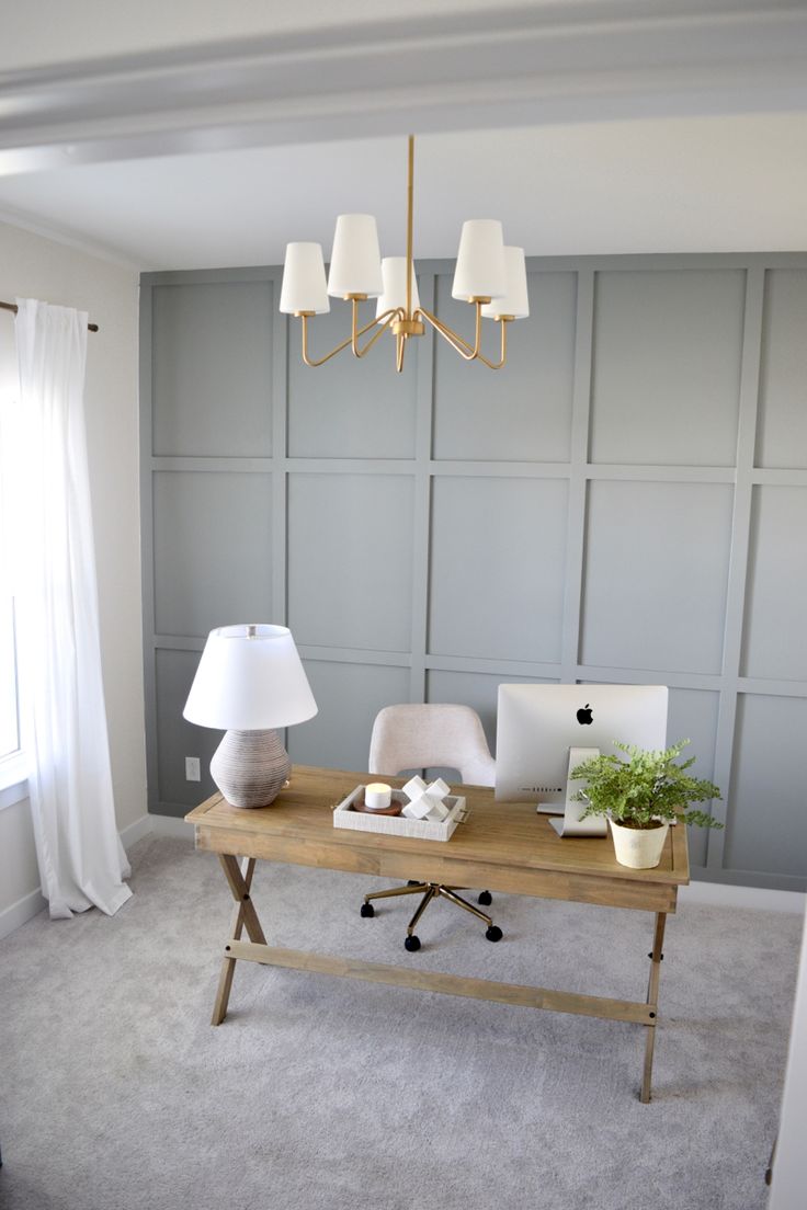 a desk with a laptop and lamp on it in the middle of a living room