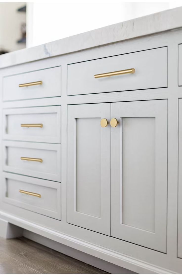 a white cabinet with gold handles and knobs on the doors is shown in this image