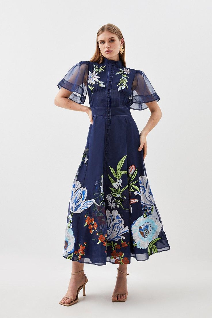 Ornate And Original, This Midi Dress Is Defined By Intricate Embroidery To The High-Neck Bodice, Offset By Semi-Sheer Long Sleeves And Tonal Buttons. Landing At A Delicately-Gathered A-Line Skirt, This Wedding-Ready Piece Calls For Tonal Stilettos And An Artful Floral Headband.High Necktonal Buttonsfloral Embroiderymidi Length Botanical Motifs, Botanical Embroidery, Dark Dress, Wedding Attire Guest, Colour Pop, Angel Sleeve, Navy Midi Dress, Bride Clothes, Midi Dress With Sleeves