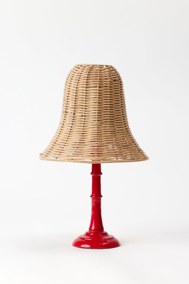 a red lamp with a straw shade on it