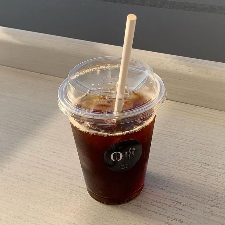 a plastic cup filled with liquid and a straw sticking out of the top, sitting on a table