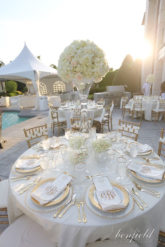 the table is set with white and gold plates, silver napkins, and centerpieces