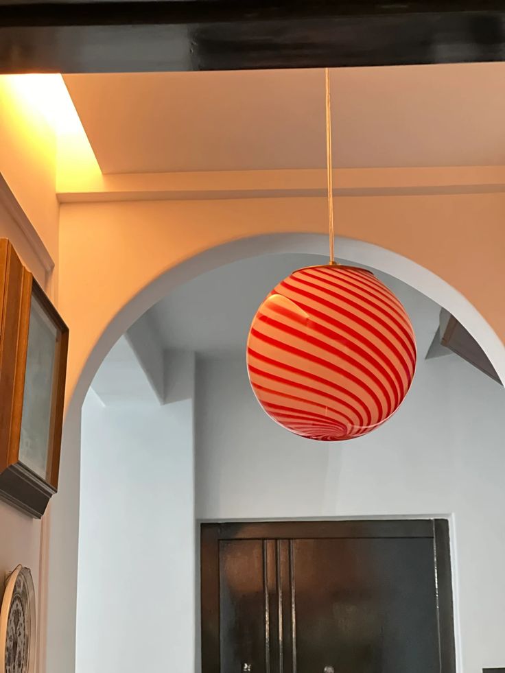 a red and white striped ball hanging from the ceiling in a room with an archway