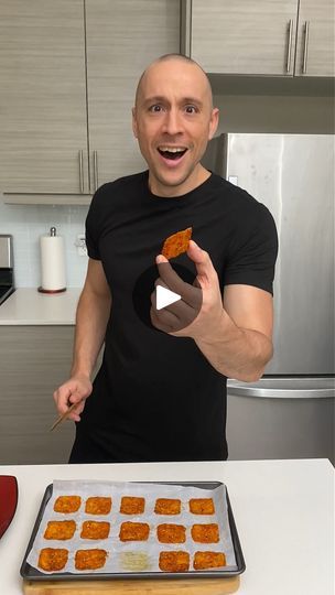 a man standing in front of a pan filled with tater tots on top of a kitchen counter