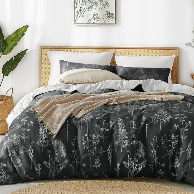 a bed with black and white comforter in a room next to a potted plant