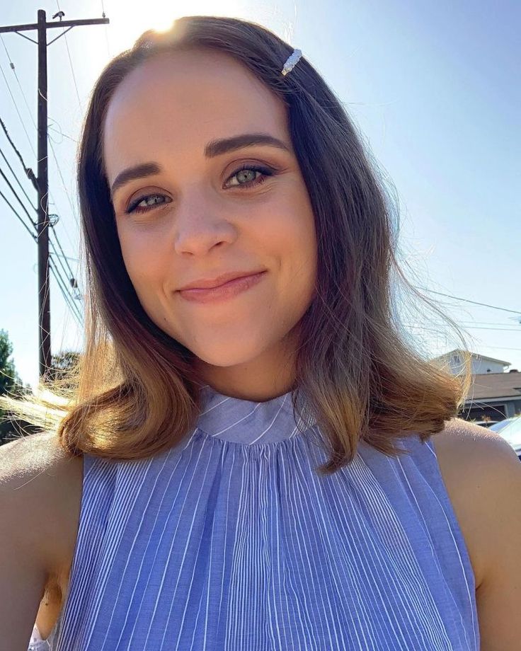 a woman in a blue dress is smiling for the camera with her hair pulled back