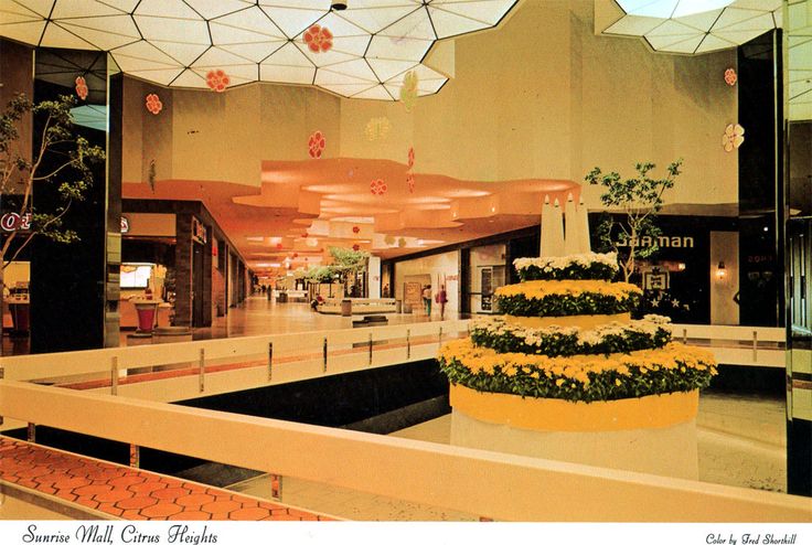 the inside of a mall with flowers and umbrellas