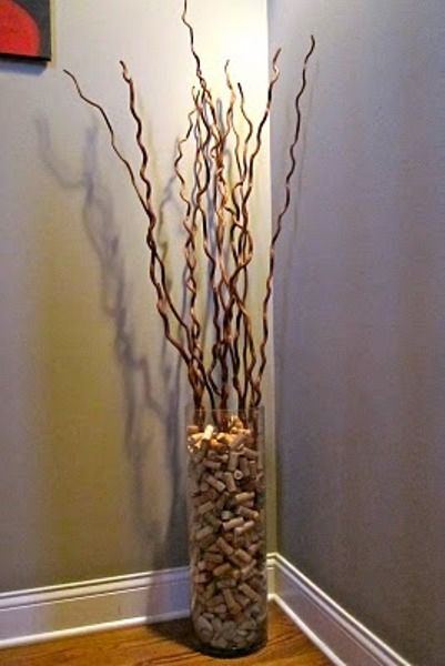 a vase filled with rocks and branches on top of a wooden floor next to a wall