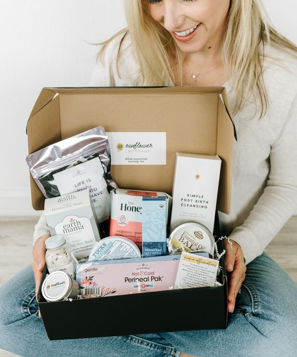 a woman sitting on the floor holding a box full of items