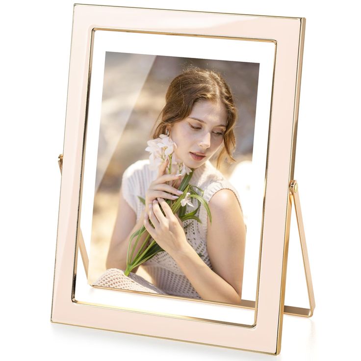 a woman holding flowers in front of her face and looking down at the ground while standing behind a gold frame