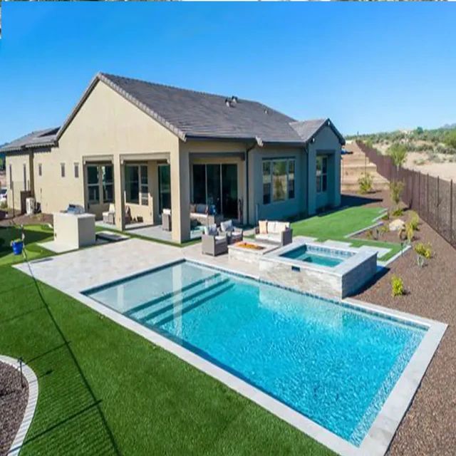 a backyard with a swimming pool and patio area in the middle of it, surrounded by grass