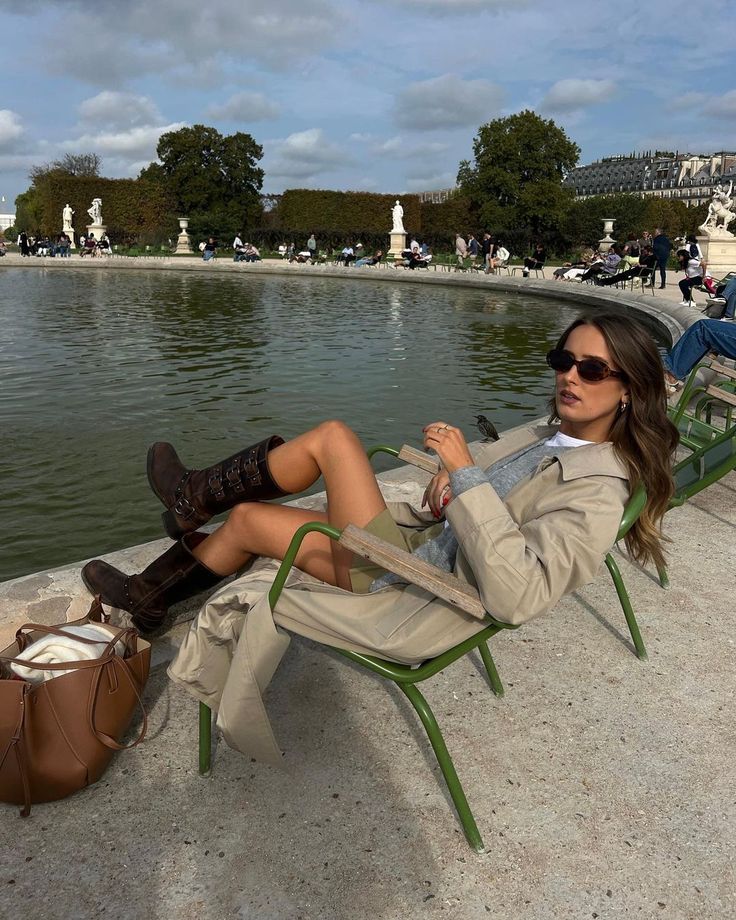 a woman sitting in a chair next to a pond