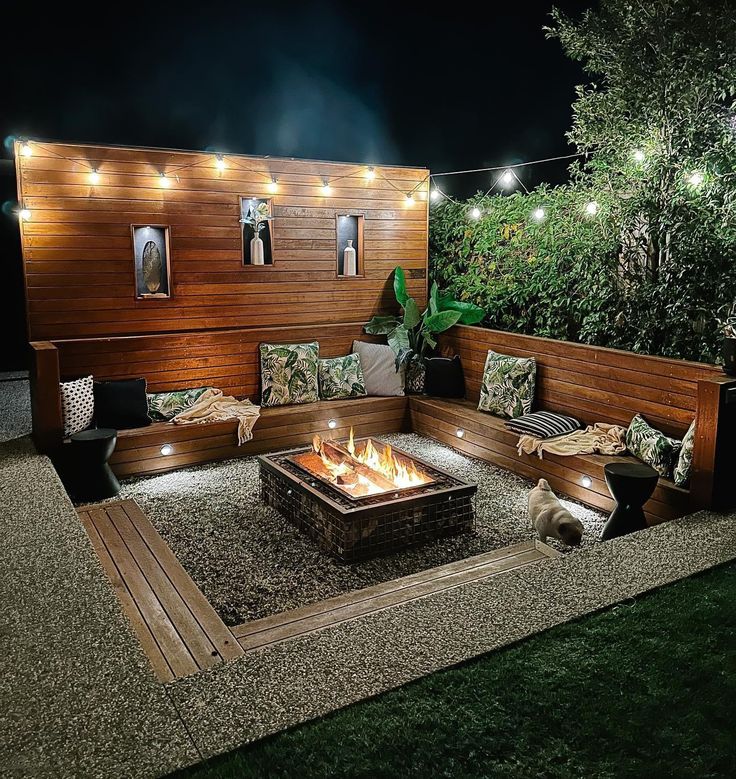 a fire pit surrounded by wooden benches and lights