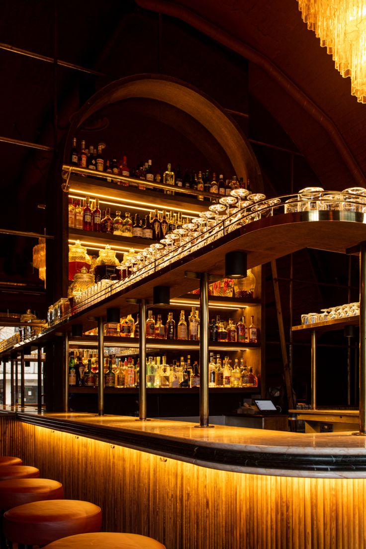 a bar with lots of bottles on the shelves and stools in front of it