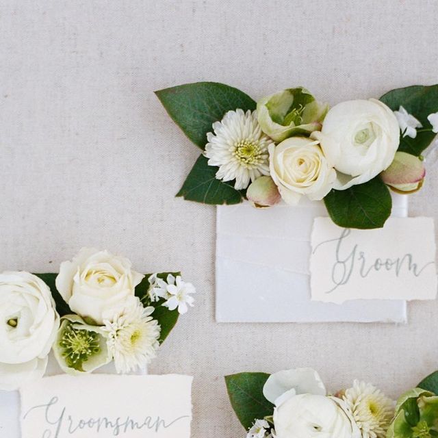 white flowers and greenery are placed on top of the place cards for an elegant wedding