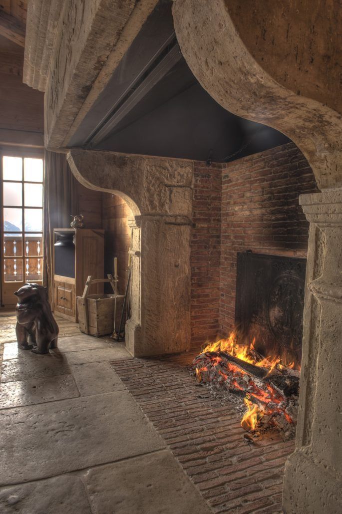 an old fireplace with fire burning in it's hearth and logs on the floor