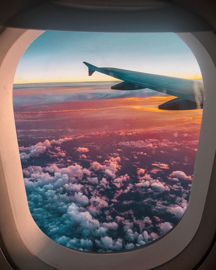 an airplane window with the view of clouds and sky from it's plane wing