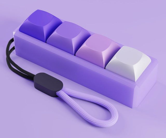 a purple and white keyboard sitting on top of a purple table next to a black cord