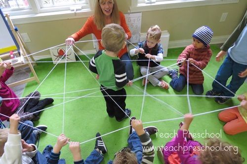 a woman teaching children how to make a spider web