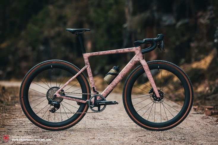 a pink bike parked on top of a dirt road