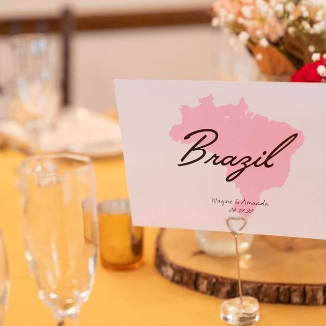 a place card is placed on a table with wine glasses and flowers in the background