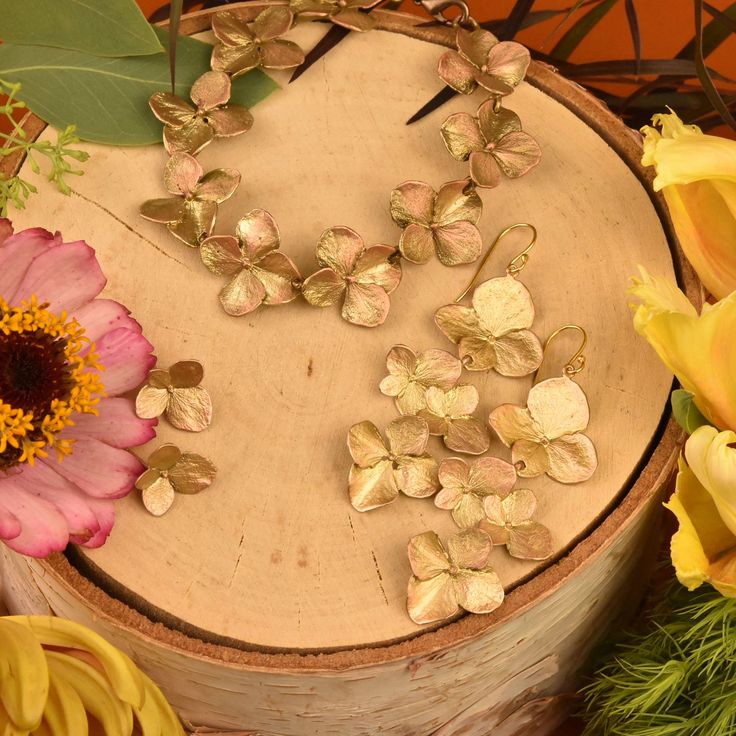 flowers and leaves are arranged on a wooden surface next to a flower pot with petals in it