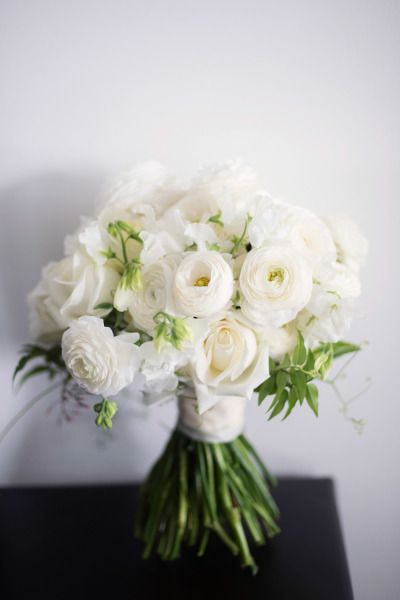 a bouquet of white flowers sitting on top of a black table next to a wall