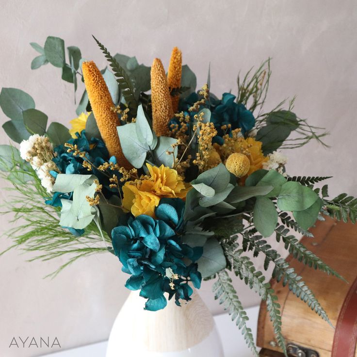 a white vase filled with flowers and greenery