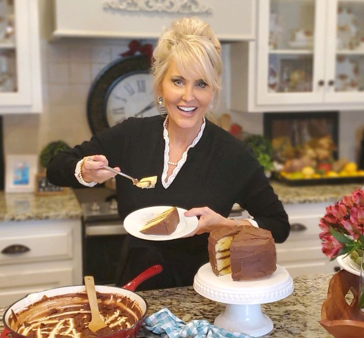 a woman is holding a fork over a piece of cake on a plate in the kitchen