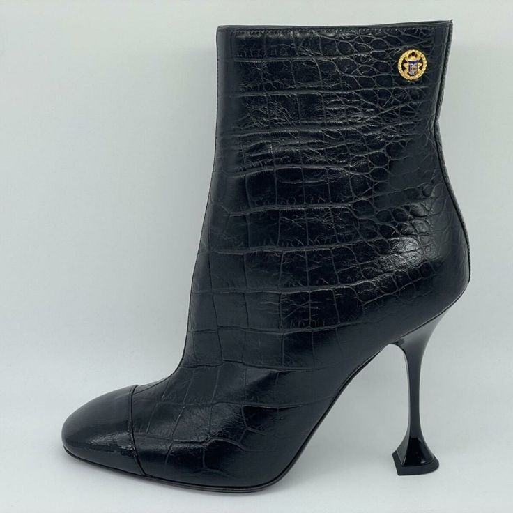 Croc Embossed Calfskin Black Ankle Boots From 2019 Mtiers D'art Paris-New York Collection. These Booties Feature A Crumpled Patent Calfskin Cap Toe And 4" Patent Leather Whimsical Heel. Goldtone Metal Cc And Blue Enamle Embossed Crest Detail On The Sides. Goldtone Cc Embossed Zipper Pull On Side Zip. Padded Leather Insole And Leather Sole. Made In Italy. Designer Color: Black. Size: 39.5 Eu (Insole Measures 10 3/8", Heel: 4"). Typically Chanel Shoes Run Small. Brand New With The Box. Luxury Ankle Boots With Sculpted Heel, Luxury Ankle Boots With 4-inch Heel, Luxury High Ankle Boots With Sculpted Heel, Luxury High Ankle Heeled Boots With Reinforced Heel, Luxury Boots With Pointed Toe And Reinforced Heel, Luxury Boots With Sculpted Heel For Office, Luxury Boots With Reinforced Heel And Pointed Toe, Luxury Ankle Heeled Boots For Office, Luxury Pointed Toe Boots With Leather Sole