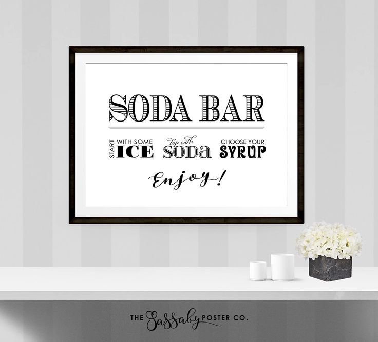 there is a white table with flowers on it and a framed sign above it that says soda bar