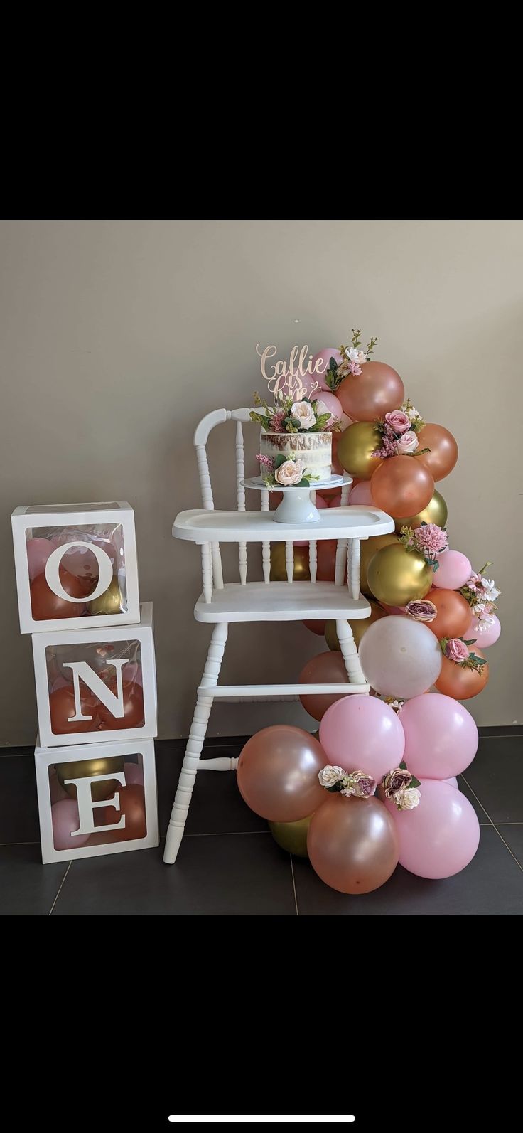 a chair with balloons on it and a sign that says one next to the chair