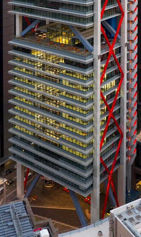 an aerial view of a tall building with red lines on the side and windows at night