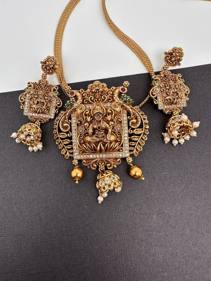 Goddess Lakshmi Nakshi Matte Finish Pendent Set It comes with Complimentary Matte Chain but can be used with any gold chain or beads. Pair it up with Saree or any Indian Attire Pendent Length Approx. 3 Inches Pearl Mala Length : Approx. 16  Inches;  Earring Length : Approx. 2.25 Inches; Push back. Comes in gift box, Ideal for gifting. Ready to ship from Boston, MA Delivery time 3-5 days. If you have any questions please let me know. Thank you!! 22k Gold Temple Jewelry Sets As Gift, Gold Kundan Jewelry Set With Peacock Design, Diwali Temple Jewelry Sets With Pendant, Gold Pendant Jewelry For Navratri, Gold Plated Temple Jewelry Set For Puja, Gold Temple Jewelry Set With Peacock Design, Heavy Gold Jewelry For Navratri, Gold Plated Temple Jewelry Sets, Gold Temple Jewelry Sets With Tilla