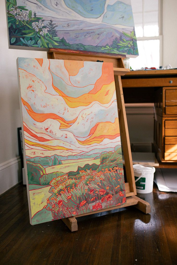 an easel with two paintings on top of it