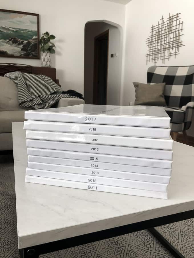 a stack of white books sitting on top of a table in front of a couch