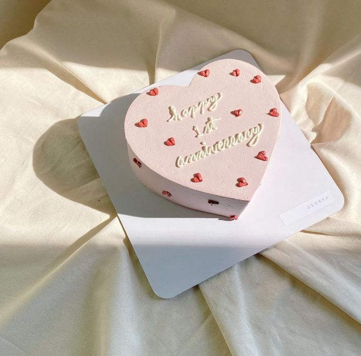 a heart shaped cake sitting on top of a white plate next to a pink box