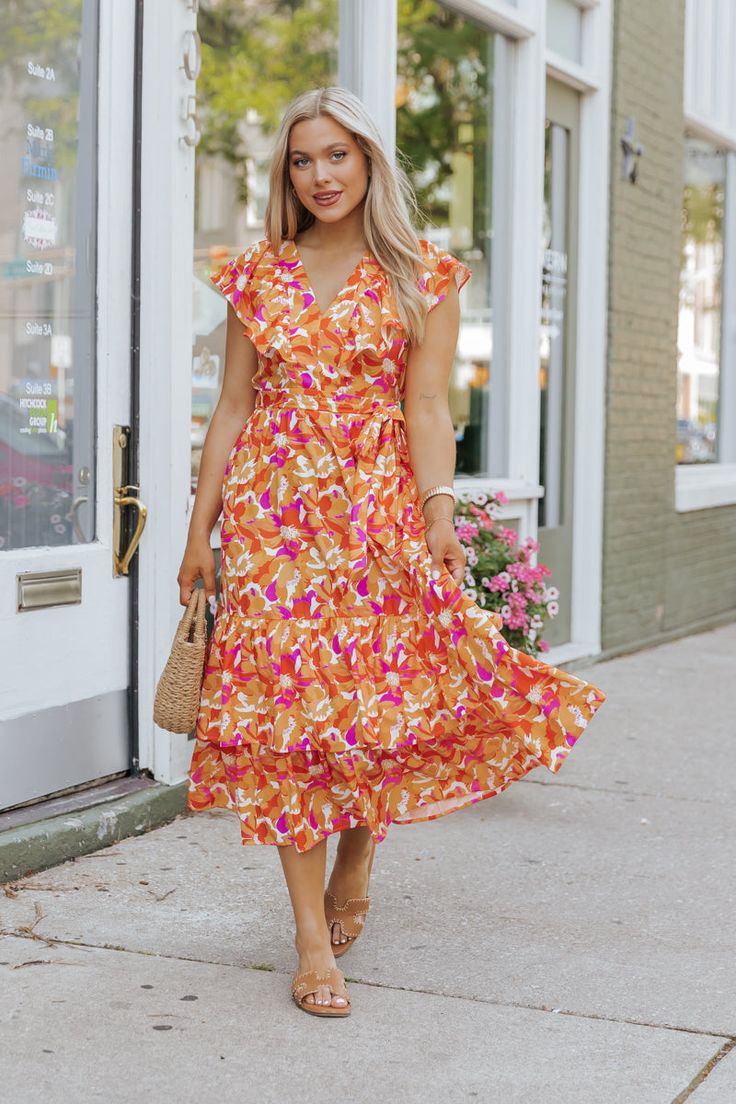 This vibrant Orange Floral Midi Dress is sure to turn heads! Our Paradise Peach Floral Tie Midi Dress is a delightful and feminine piece perfect for adding a touch of romance to your summer wardrobe! The vibrant orange floral print adds a cheerful and feminine touch to the dress, perfect for summer outings and picnics in the park! The tie front detail adds a flattering cinched-in waistline and allows you to adjust the fit to your preference. Pair with comfy sandals for a relaxed and effortless daytime look or dress it up with some strappy high heels. Accessorize with statement earrings and a clutch bag to finish the look. Orange Ruffled Dress For Garden Party, Vibrant V-neck Midi Dress For Brunch, Orange Summer Midi Dress With Ruffles, Summer Orange V-neck Midi Dress, Orange Sundress For Summer Brunch, Orange Ruffled Midi Dress For Vacation, Floral Print Midi Dress For Summer Parties, Peach V-neck Spring Dress, Multicolor Summer Midi Dress For Garden Party