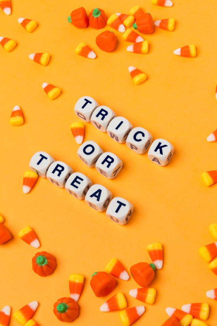 the word trick or treat spelled out with candy corn and candies on an orange background