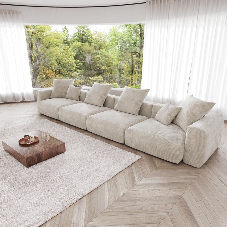 a living room with a large sectional couch and coffee table in front of the window