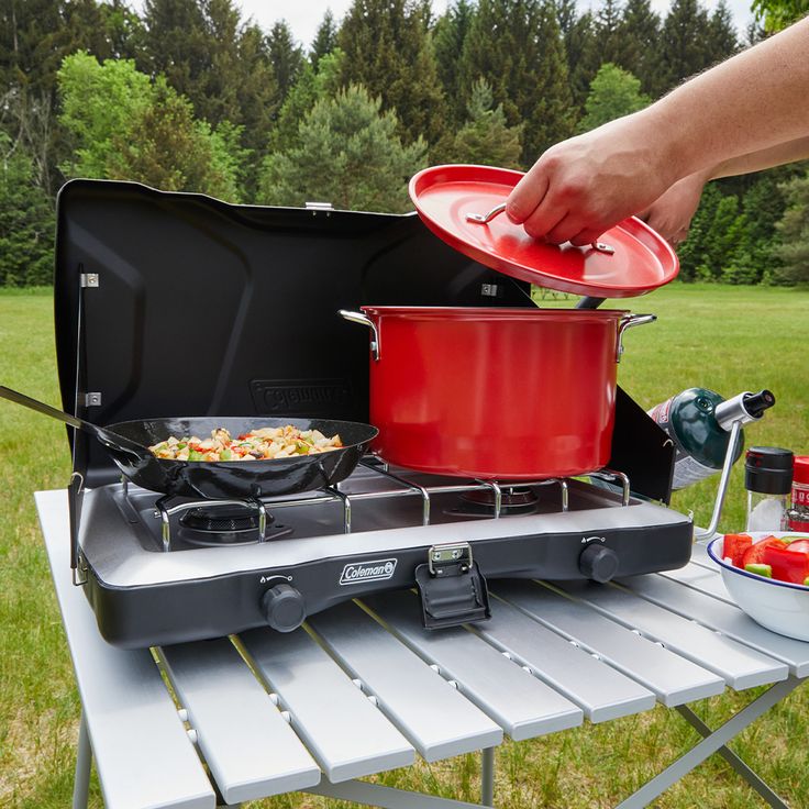 a person is cooking food on an outdoor stove