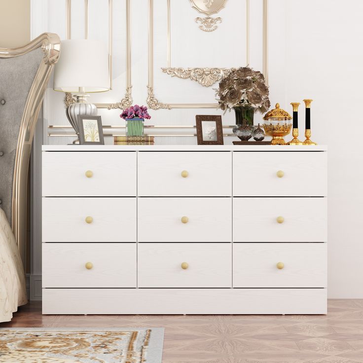 a white dresser sitting next to a bed in a room with gold trimmings