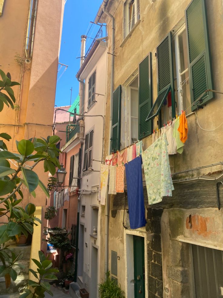 clothes hanging out to dry on a line in an alleyway with buildings and green shutters