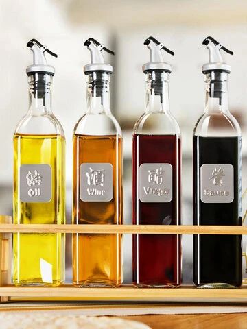 four bottles of different types of oil on a wooden tray in front of some bread