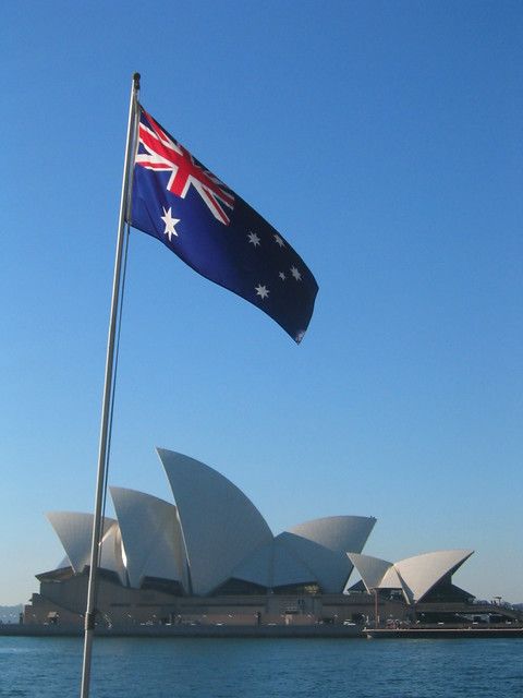 an australian flag flying in front of the sydney opera house