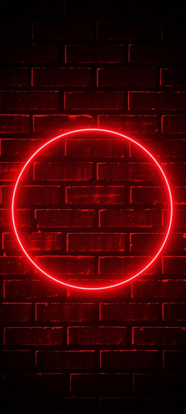 a red neon sign on a brick wall with a circular shape in the middle, against a dark background