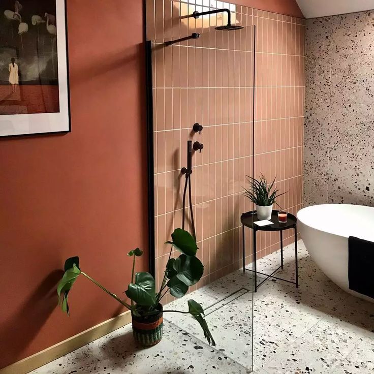 a bath tub sitting next to a white sink in a bathroom under a window with potted plants on it