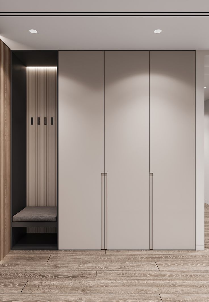 an empty room with white closets and wooden flooring on the walls, along with a bench